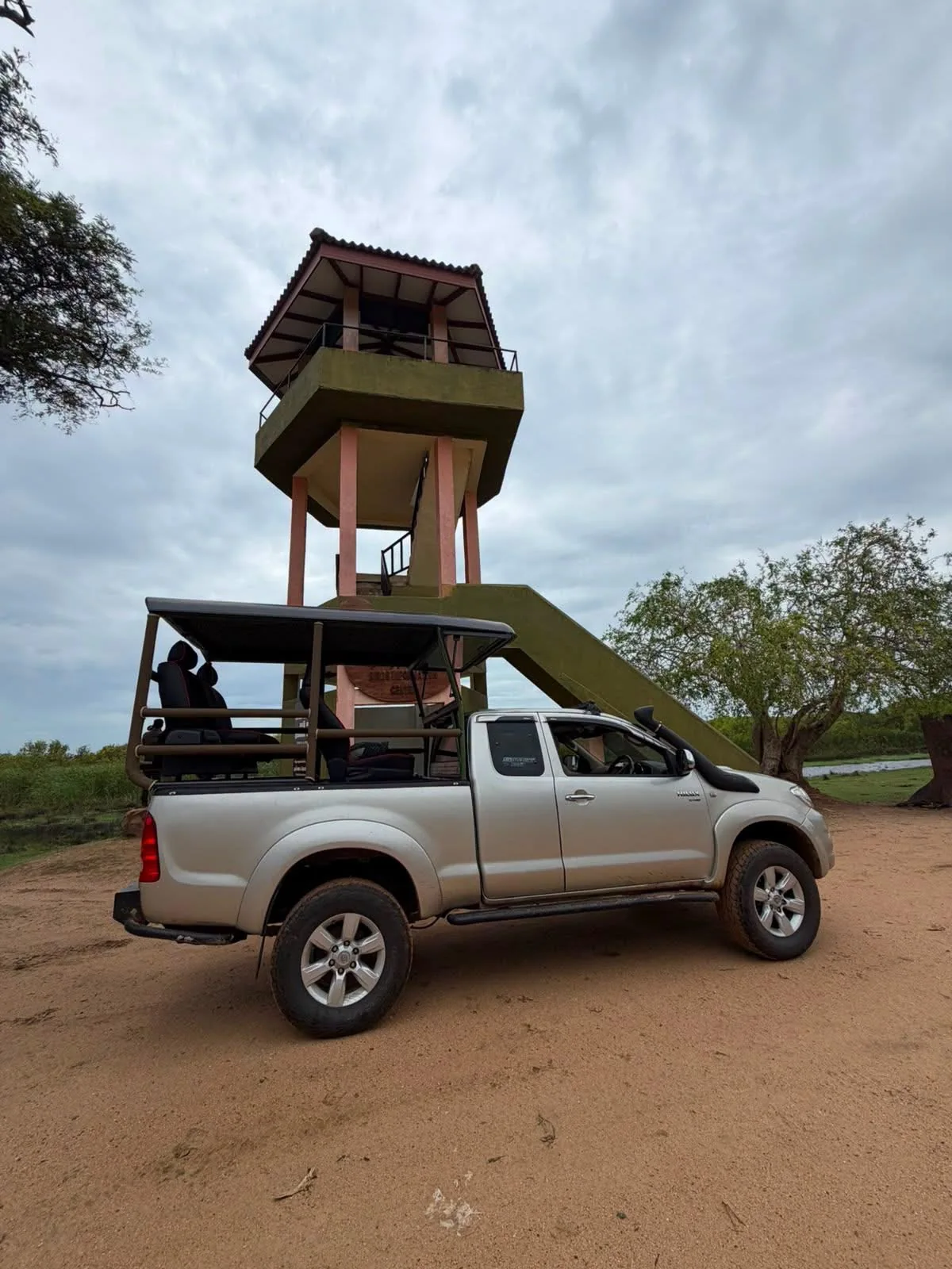 An open safari jeep parked beside the observation tower at the Kumana Villu stopping area.